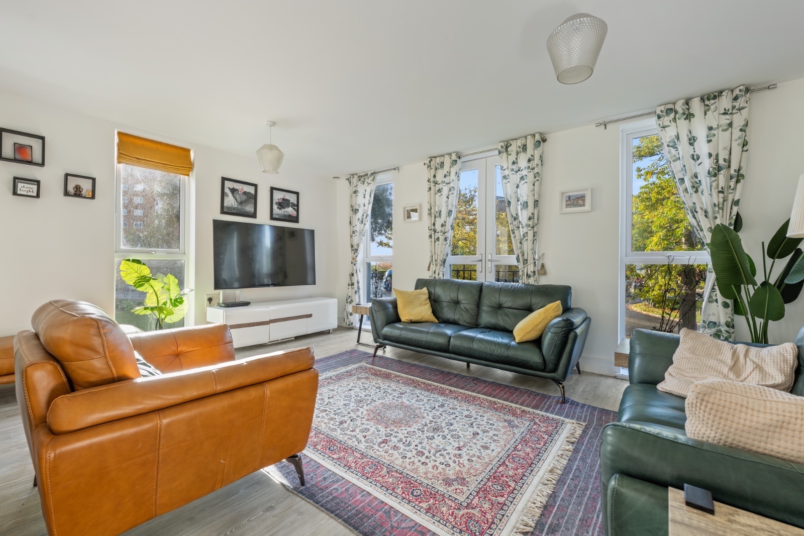 Living room with leather sofas, green velvet armchairs and south-facing windows