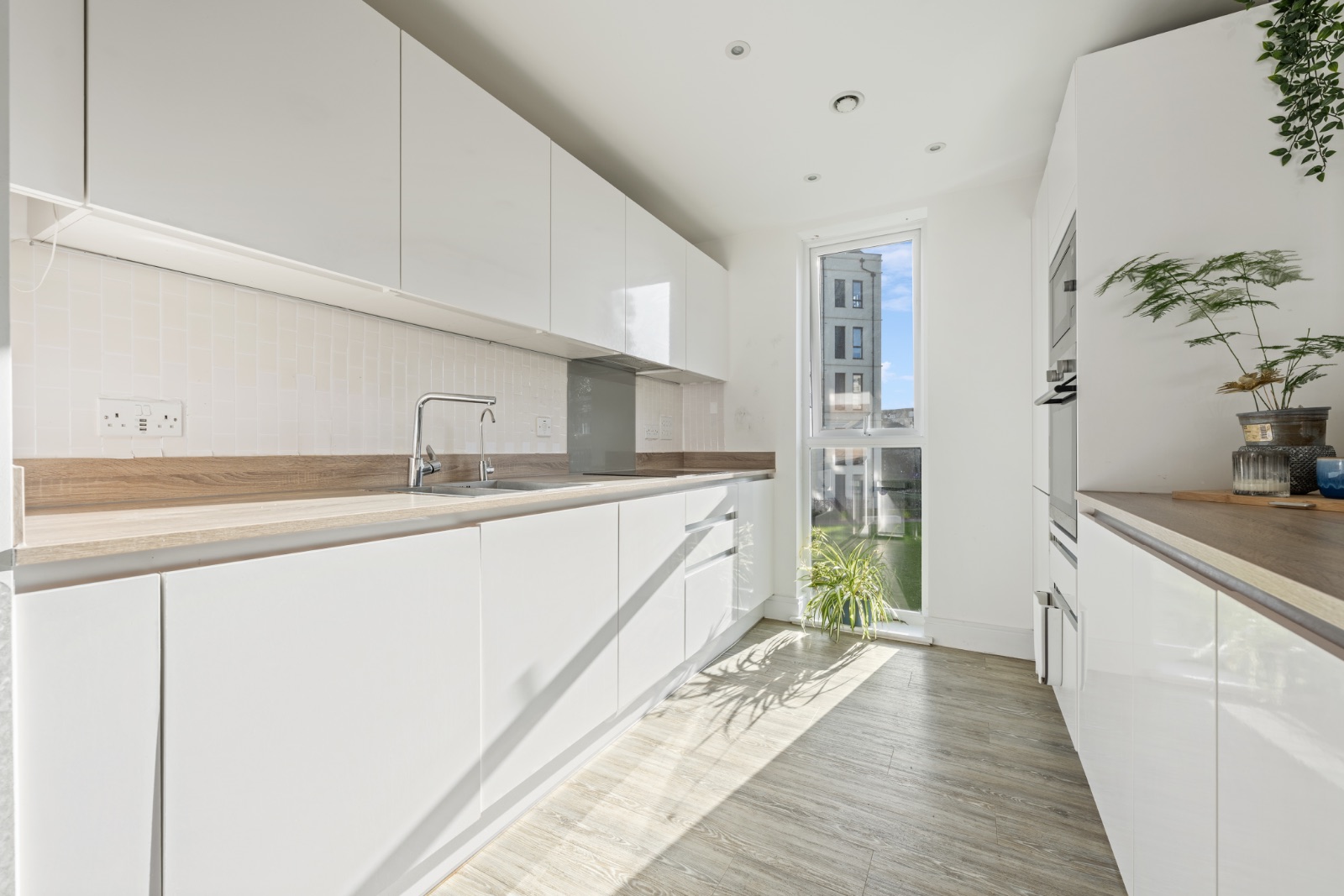 Modern white galley kitchen with wood-effect worktops and Bosch appliances